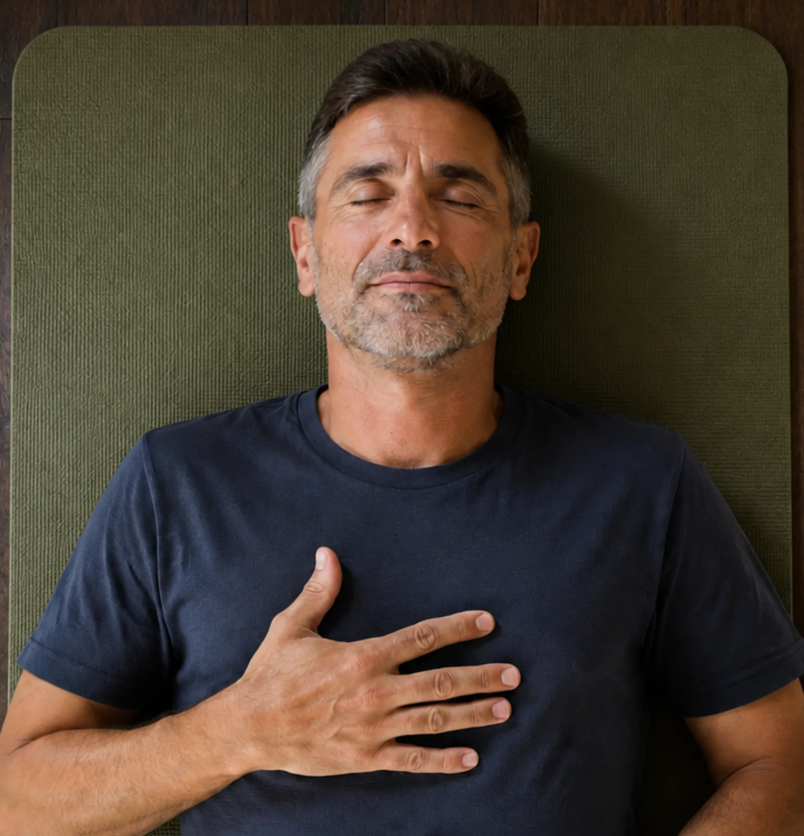 Man in breathwork practice, hand on chest, lying on yoga mat